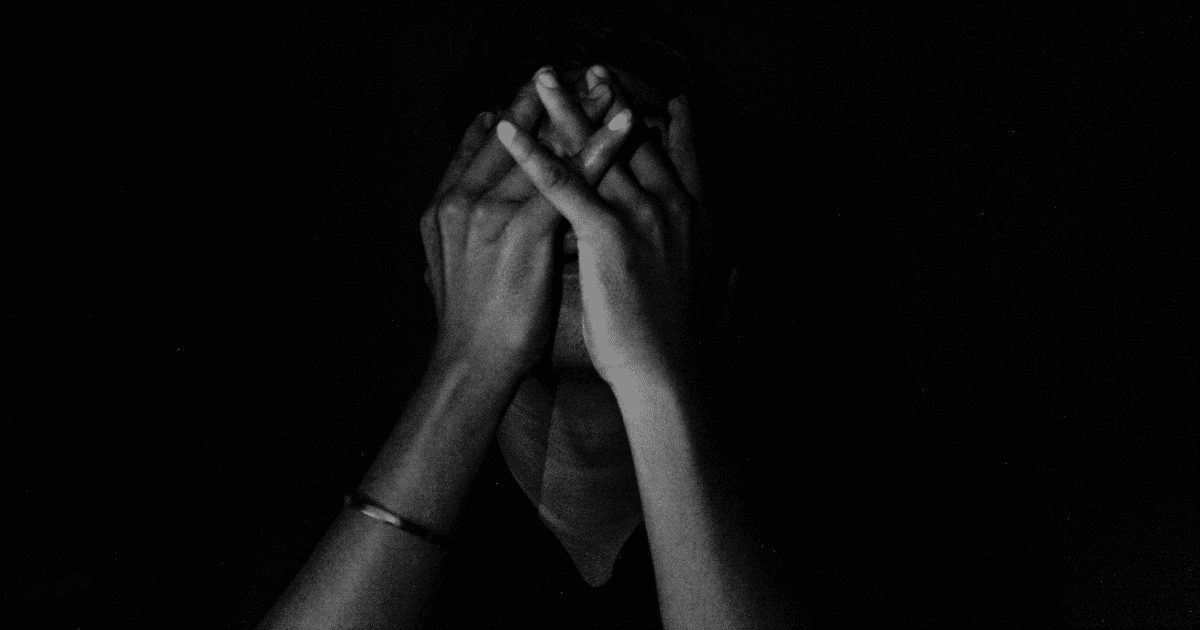 person in dark background seemingly stressed 