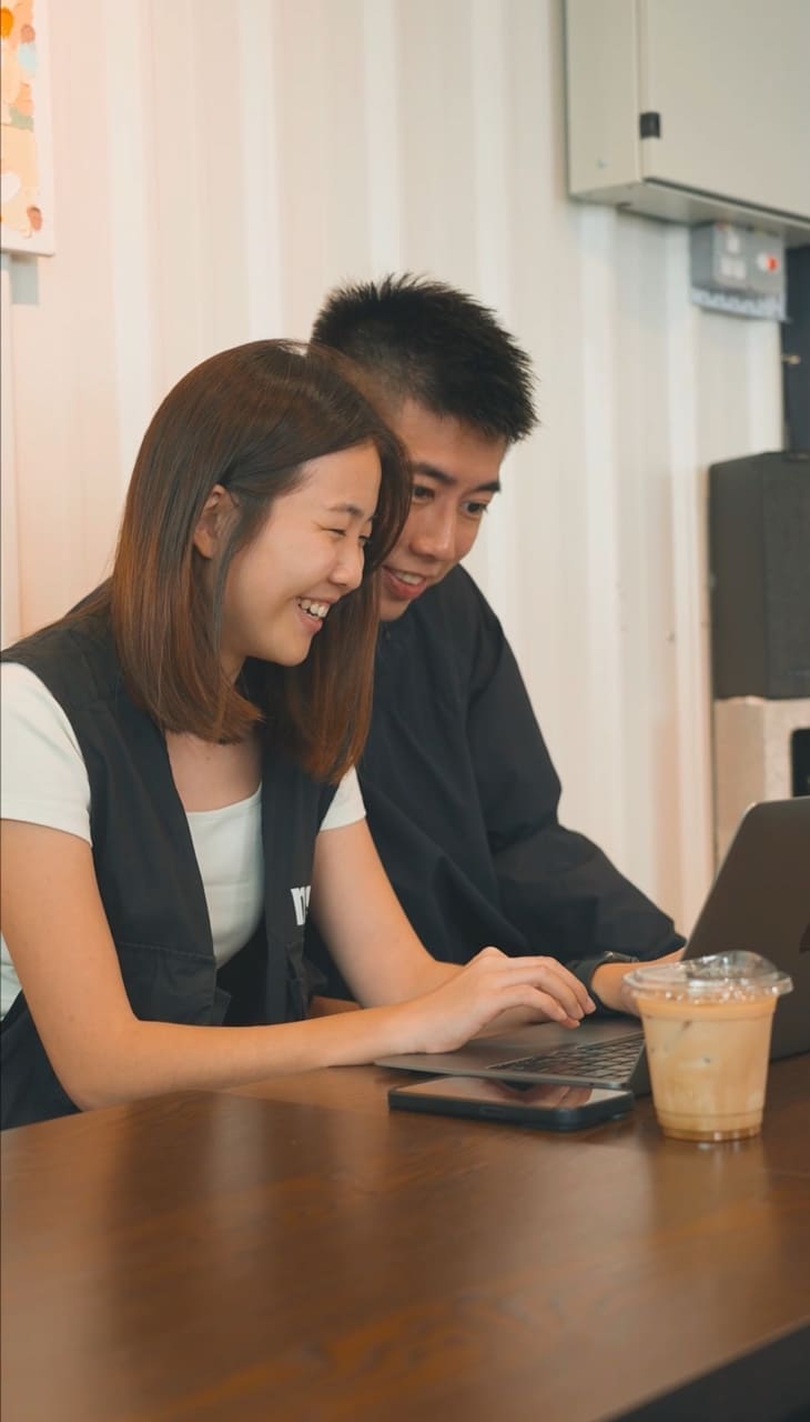 Nik and Jing smiling at the laptop