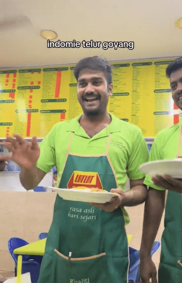 mamak staff talking to customer while serving food