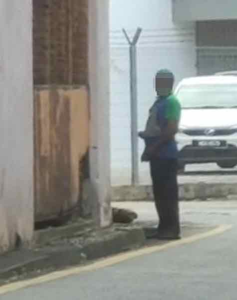 man urinating behind a premise