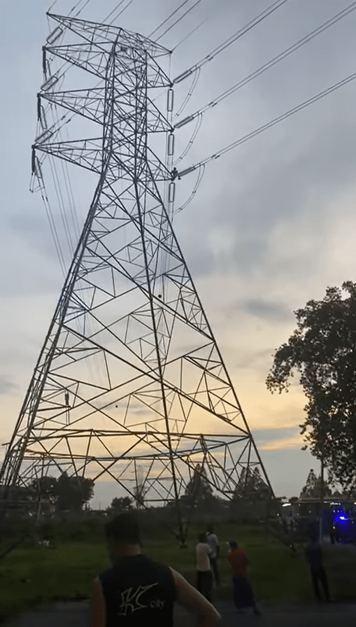 M'sian man sits on transmission tower's crossarm