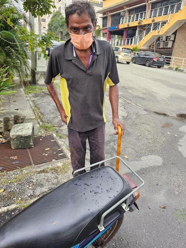 msian man standing next to his motorbike