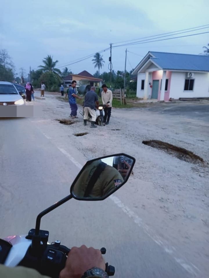 people are trying to move motorbike that was trapped in the pothole in kedah