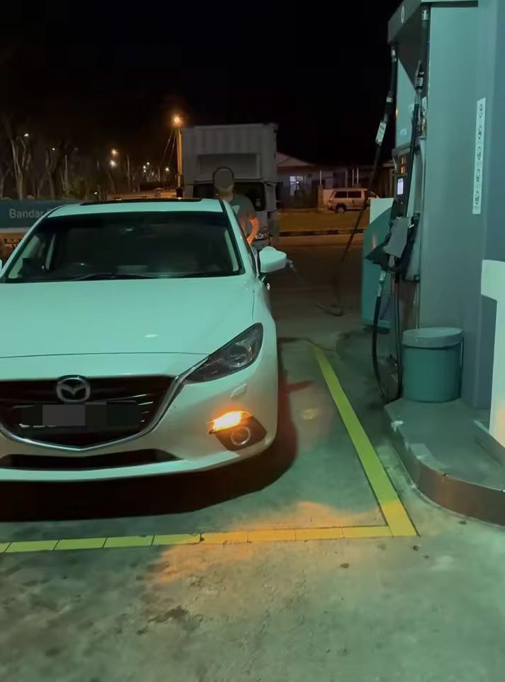 Photo of man caught pumping RON95 into SG-registered car