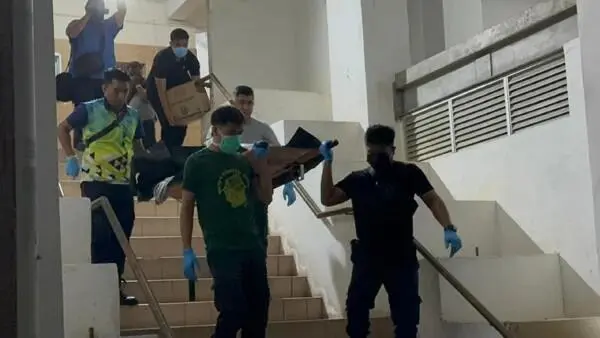 Police carrying dead body down the stairs at Penang flat