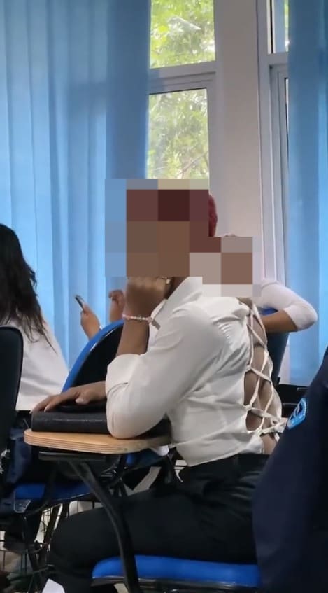 Male student sitting in a lecture class wearing revealing backless clothe. 