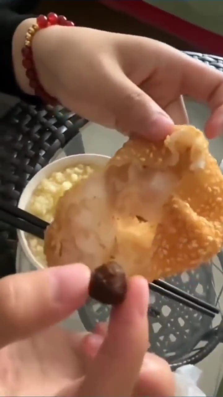 Msian woman holding a pea sized of red bean filling inside the sesame ball.