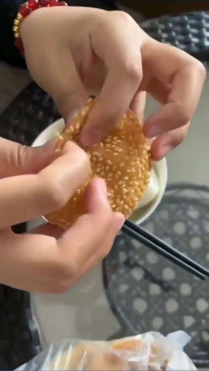 Msian woman opening a sesame ball. 