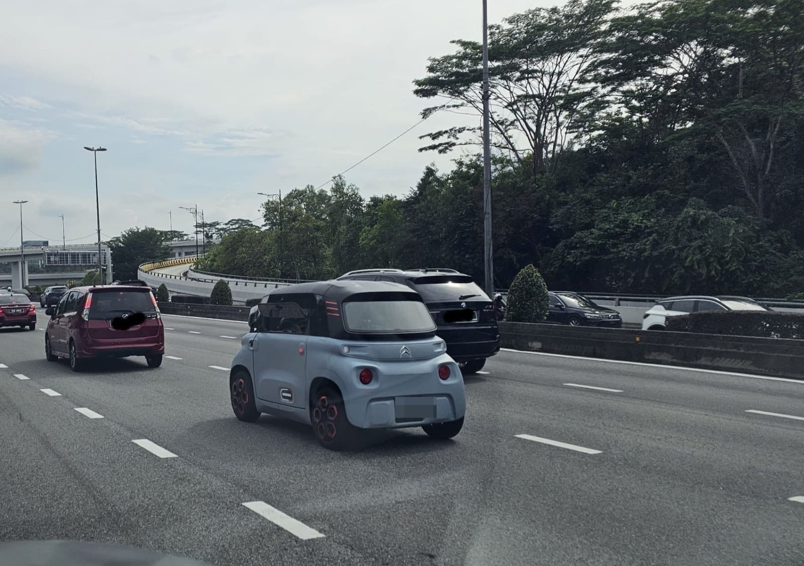 A 2-seater blue Citroen Ami pass another car on a road